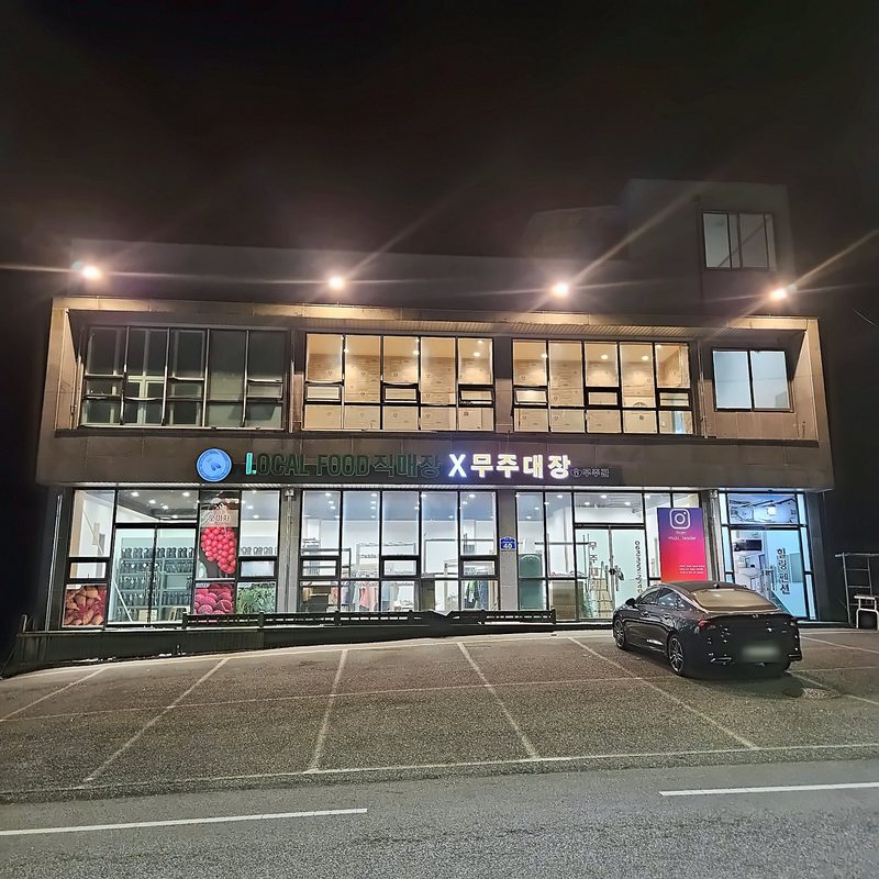 밤에 불을 밝힌 무주대장 매장 외관과 앞 주차장
